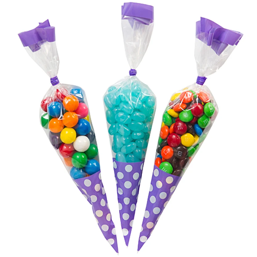 Three cone-shaped clear bags with purple polka dots filled with colorful candies