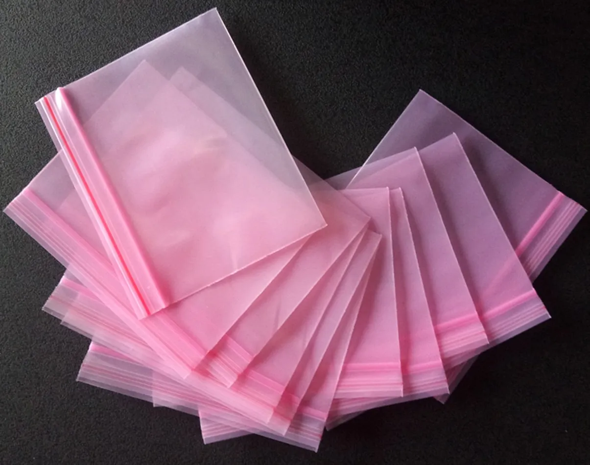Stack of translucent pink resealable plastic bags fanned on black surface