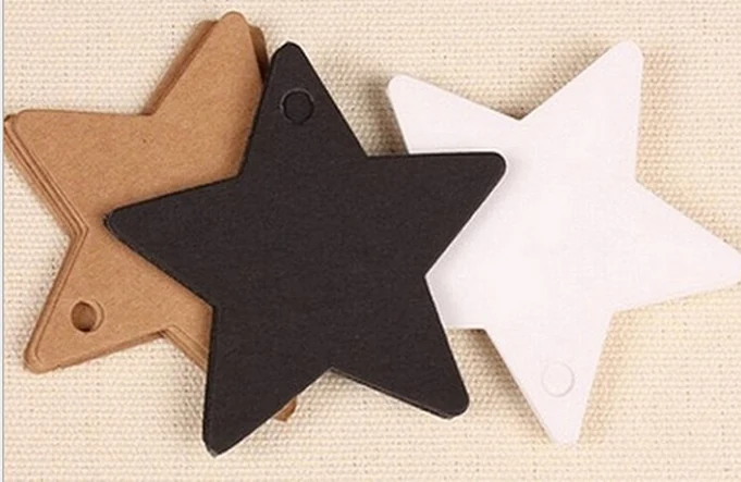 Three star-shaped paper tags in brown, black and white on beige fabric