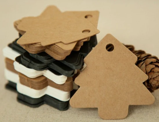 Stacks of Christmas tree-shaped kraft paper gift tags beside a pinecone