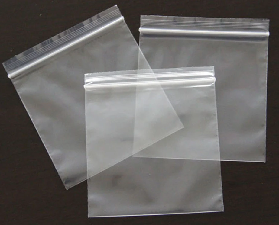 Three clear resealable plastic zip bags arranged on dark background