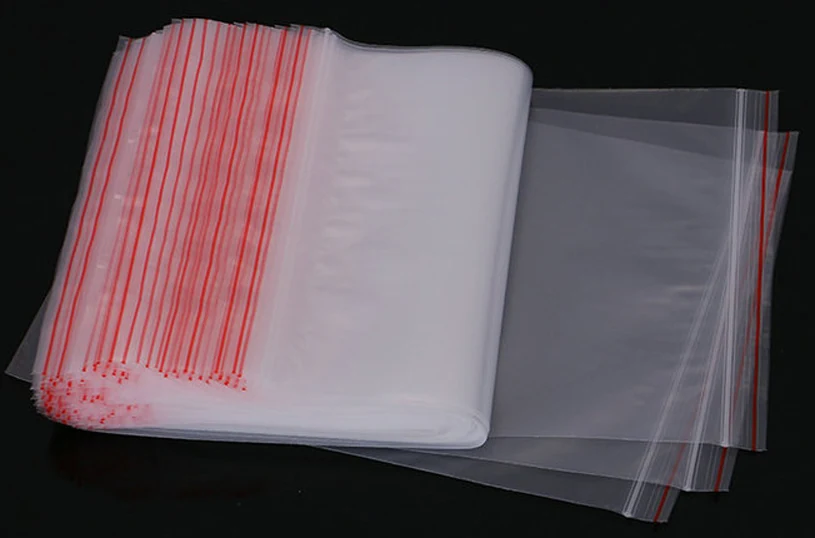 Stack of clear resealable plastic bags with red zip seals on white background