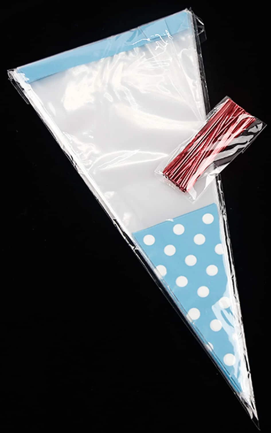 Clear plastic cone bag with blue polka dot base and red twist ties on black background