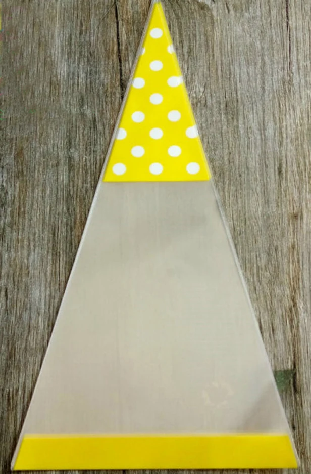 Clear cone-shaped cello bag with yellow polka-dot top on wooden surface