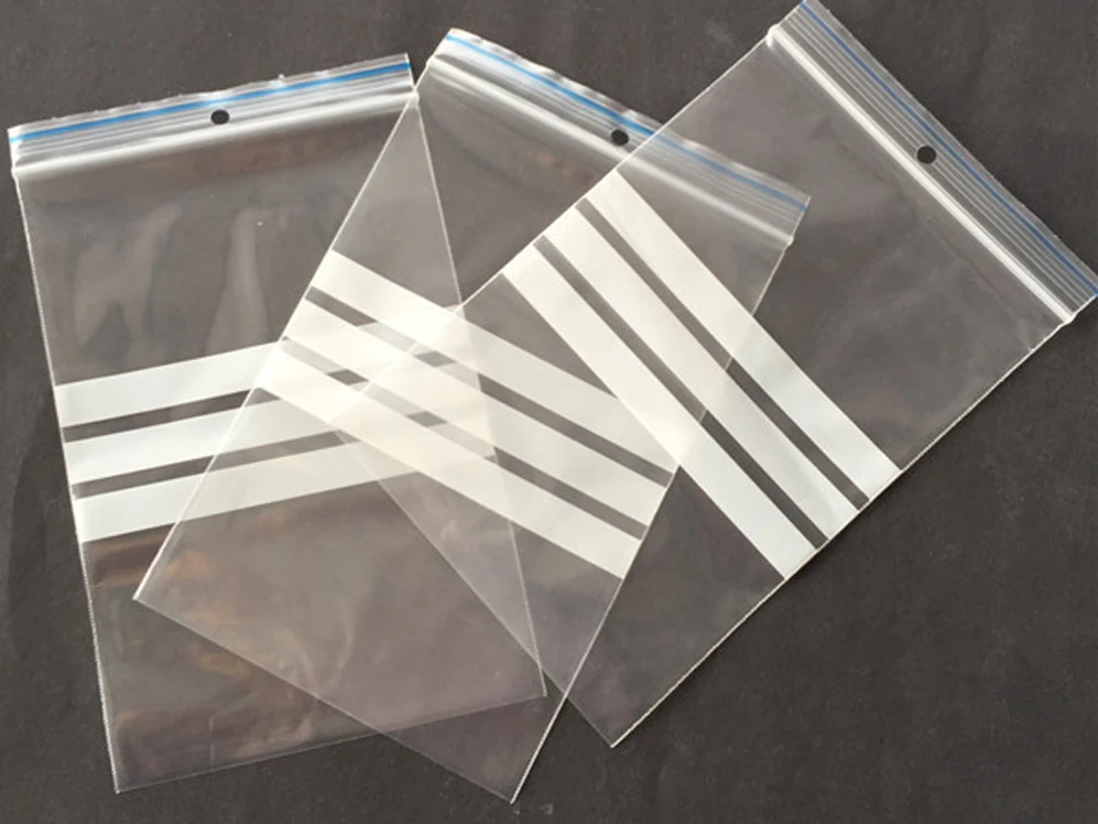 Three clear resealable plastic bags with white stripes on dark background