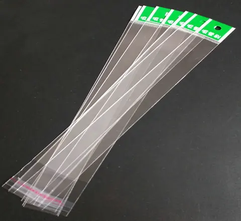 Transparent long plastic bags with green header cards arranged on black surface