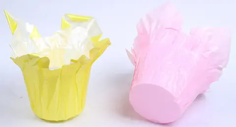 Yellow and pink tulip-style paper baking cups on white background