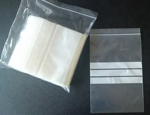 Stack of clear resealable zip bags and one single bag on black surface