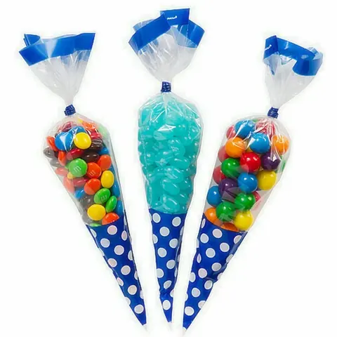 Three blue polka-dot cone bags filled with colorful candies on white background