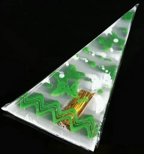 Clear cone plastic bag with green butterfly print and gold twist ties on black background