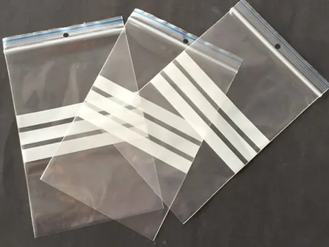 Three clear resealable plastic bags with white stripes on dark background