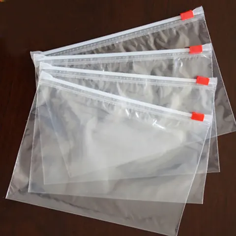 Four clear resealable plastic bags with red sliders stacked on dark table