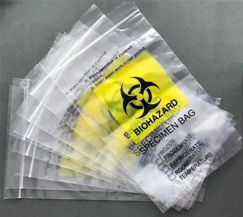 Stack of clear plastic biohazard specimen bags with yellow labels on gray surface