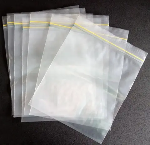 Clear resealable plastic zip bags fanned out on dark surface