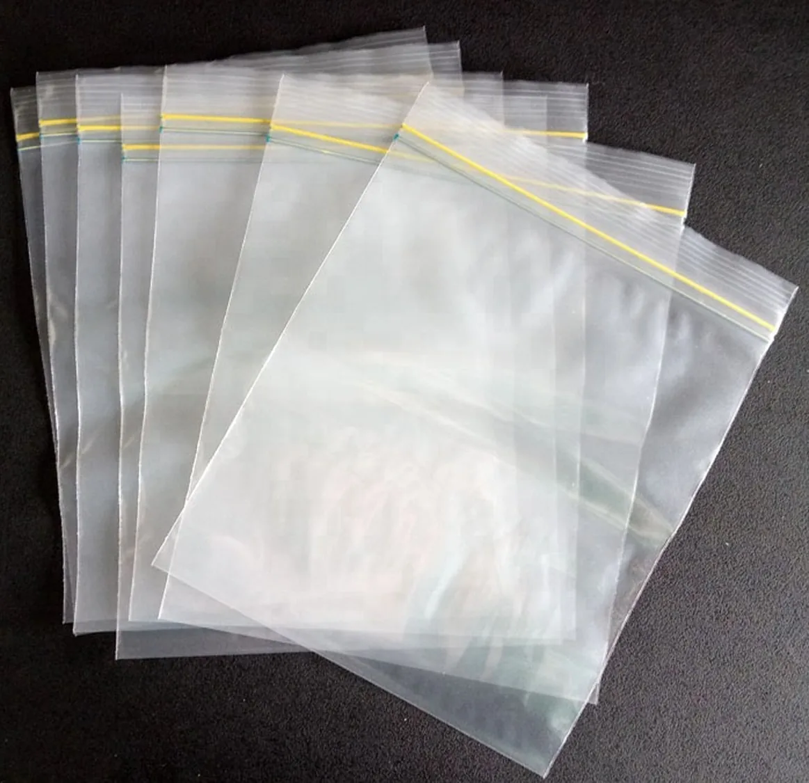 Clear resealable plastic zip bags fanned out on dark surface