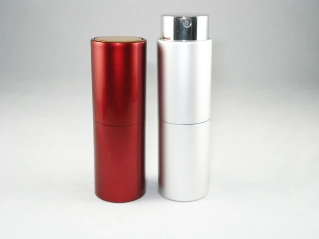 Two cylindrical aluminum spray bottles, one red and one silver, standing on a white background