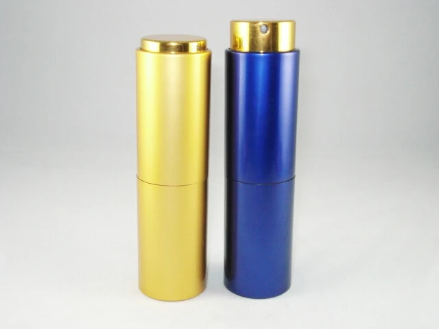Two aluminum spray bottles, one gold and one blue, with gold pump caps on a light gray background
