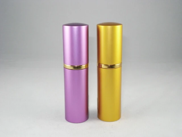 Two cylindrical cosmetic containers, one purple and one gold, with a gold band in the middle, on a white background.