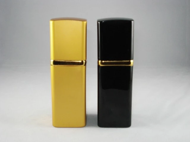 Two rectangular cosmetic bottles, one gold and one black with gold collar bands, on a white background