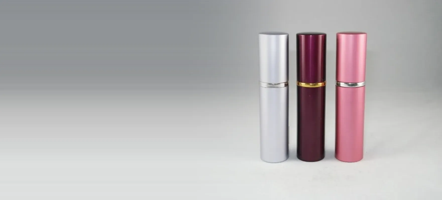 Silver, aubergine and pink cosmetic packaging tubes standing on a studio sweep