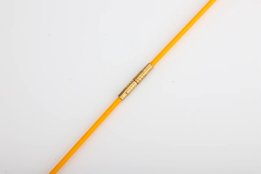 Fiberglass rods being pushed through a straight metal conduit in a wall cavity