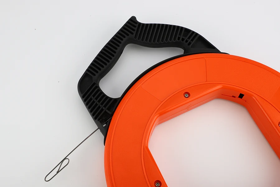 Steel fish tape being fed into electrical conduit with the leader tip visible