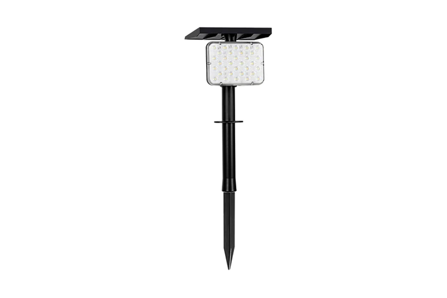 Solar spot light mounted on a wall with the solar panel facing upward, illuminated at night