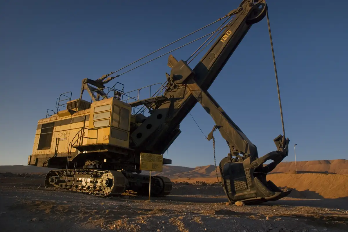 Electric rope shovel with dipper raised at a mine bench