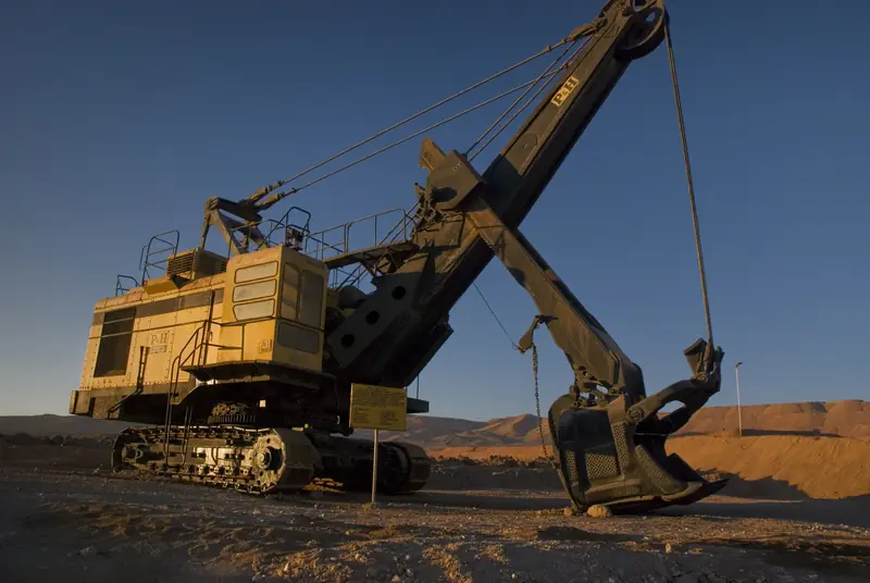 Electric rope shovel with the dipper raised at a mine face