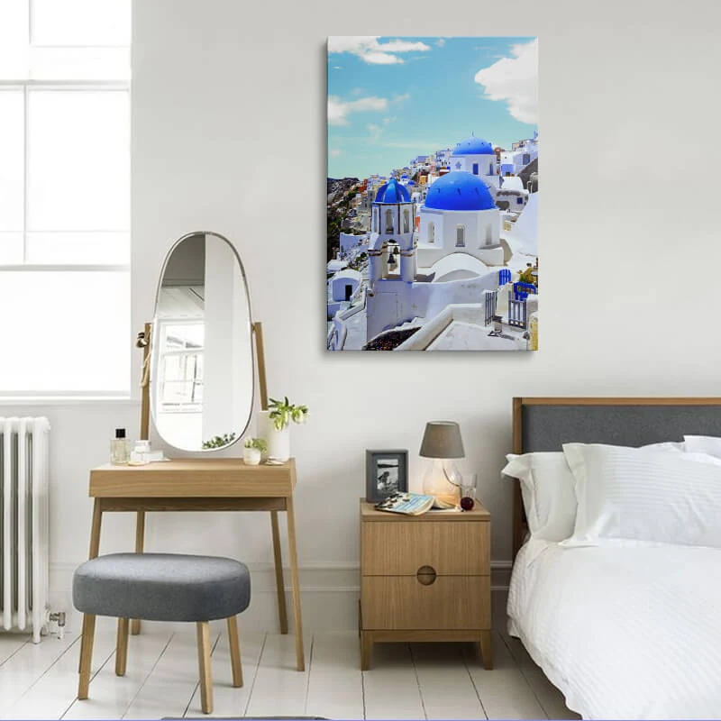 Blue Dome Church Santorini canvas hung in a bedroom above a bedside table