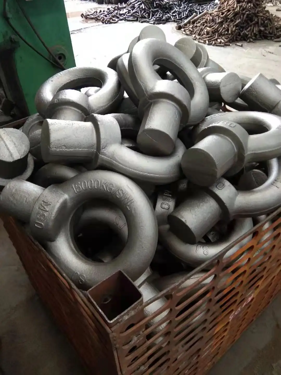 A pile of silver galvanized lifting eye bolts stacked in a crate