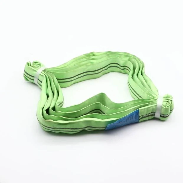 Coiled green polyester round lifting sling with dark stripes and a blue tag on a white background