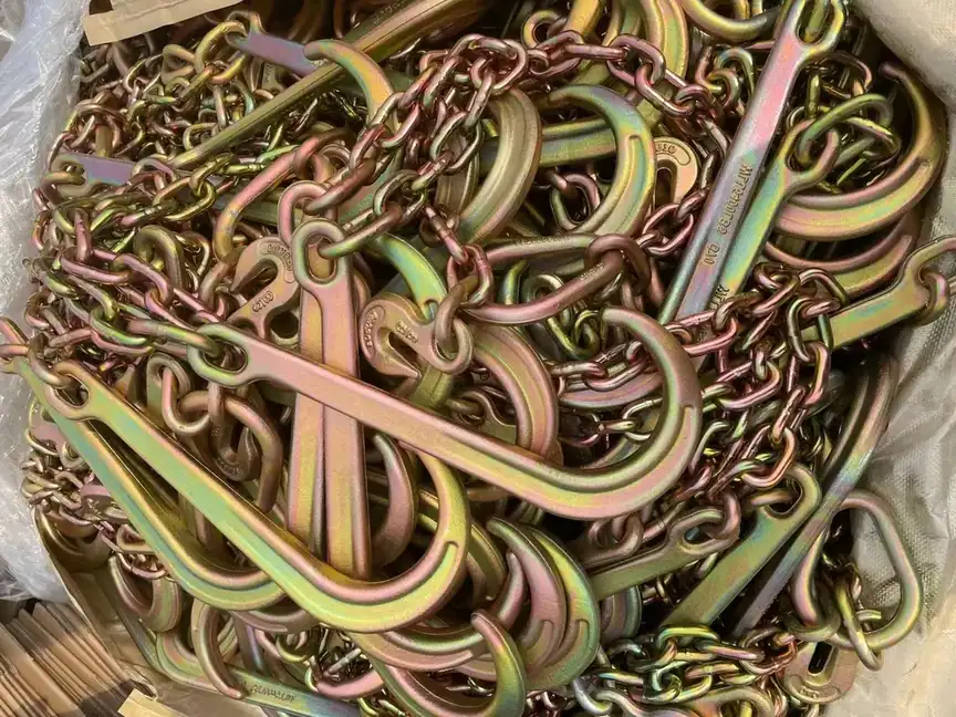 Pile of yellow zinc-plated chain slings with grab and clevis hooks, bulk packed
