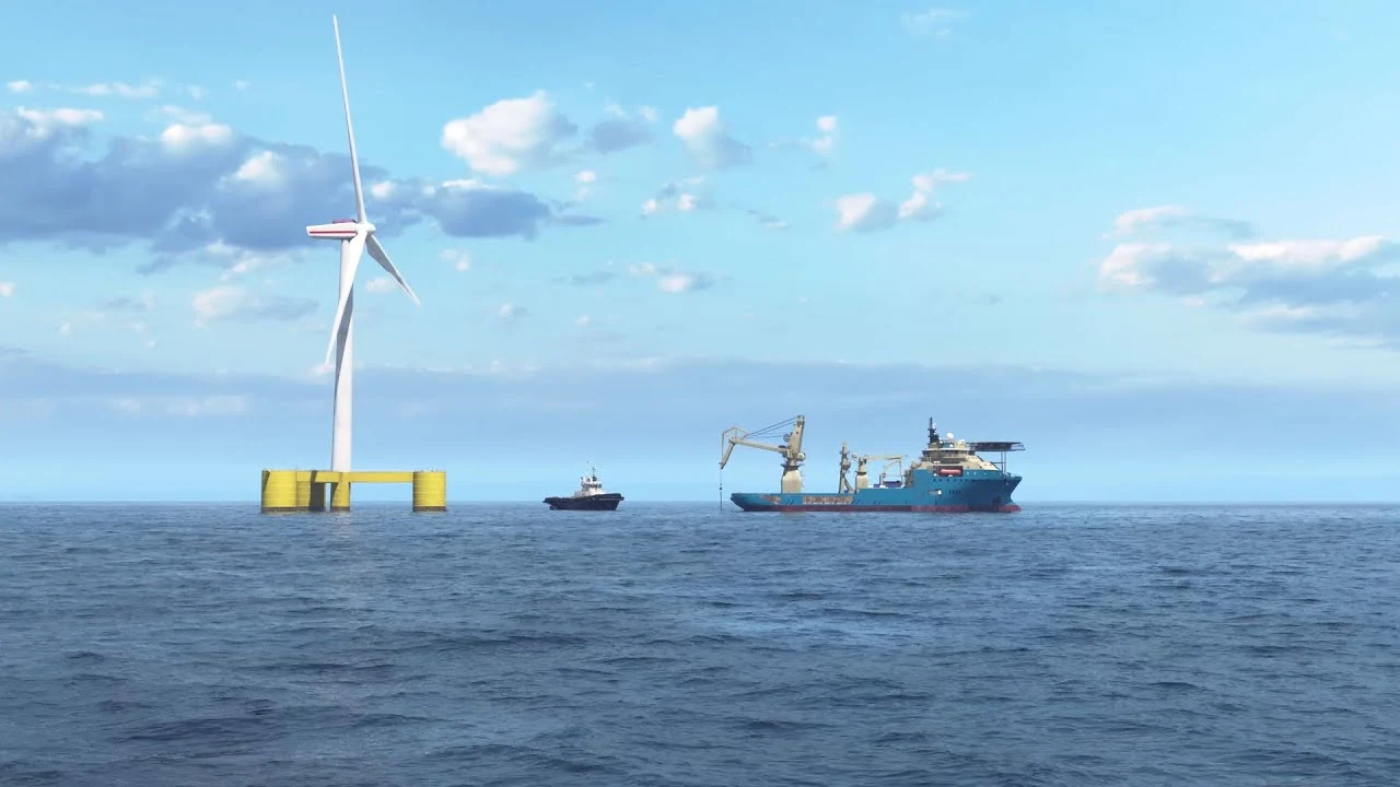 Floating offshore wind turbine on a yellow platform at sea with a blue service vessel and small tugboat nearby