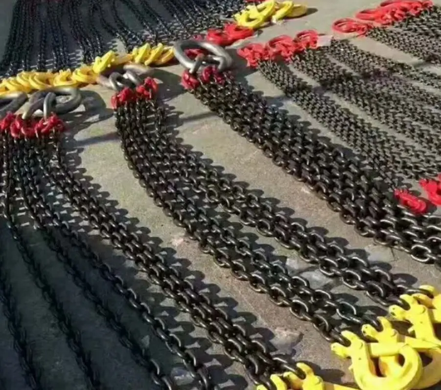 Multiple black metal lifting chains with red and yellow connectors arranged on the ground