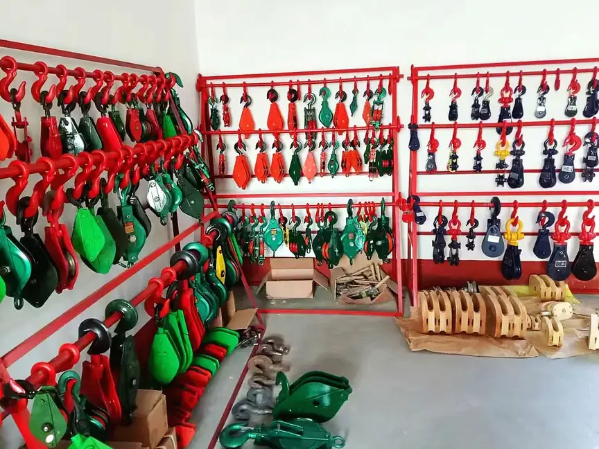 Industrial lifting hooks, swivels, and rigging hardware hanging on red display racks in a warehouse