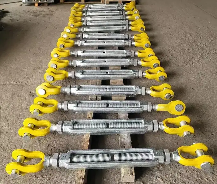 A row of turnbuckles with yellow eye ends and silver bodies on a wooden pallet