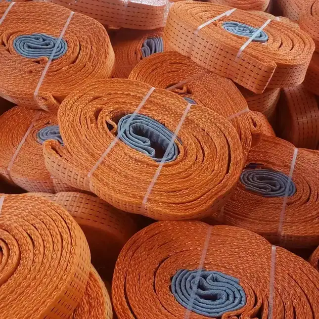 Coiled orange webbing lifting straps with blue inner loops, bundled with white bands and stacked in piles