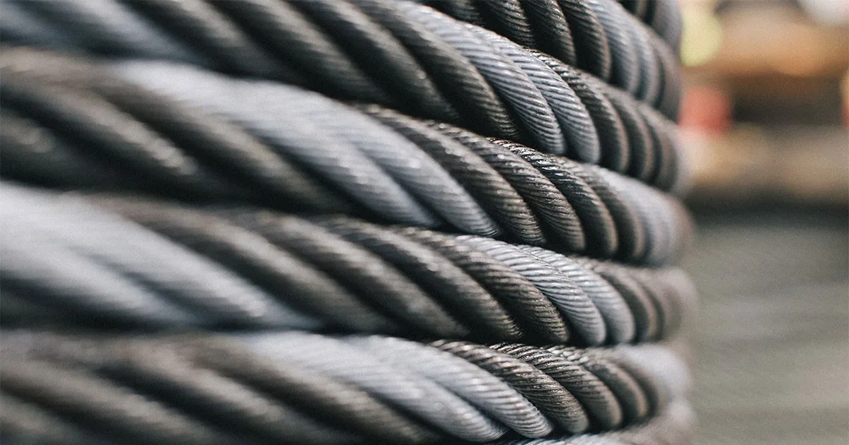 Close-up of coiled steel wire rope with twisted silver strands against a blurred industrial background