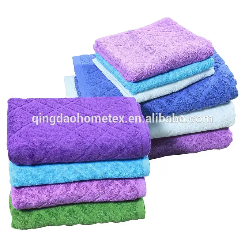 Stacks of folded purple, blue, teal and green jacquard towels on a white background