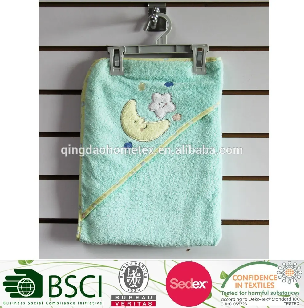 A mint green hooded baby towel with embroidered moon and star hanging on a display rack.