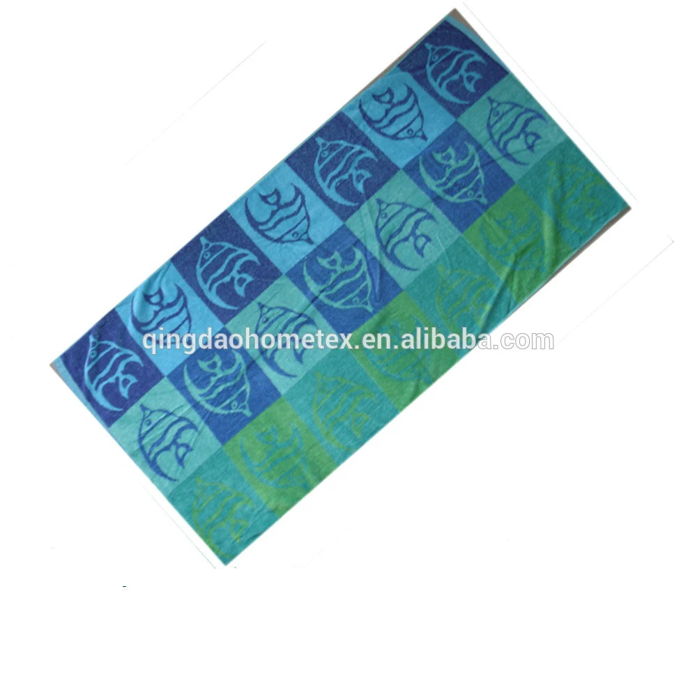 Blue and green beach towel with fish pattern lying diagonally on a white background