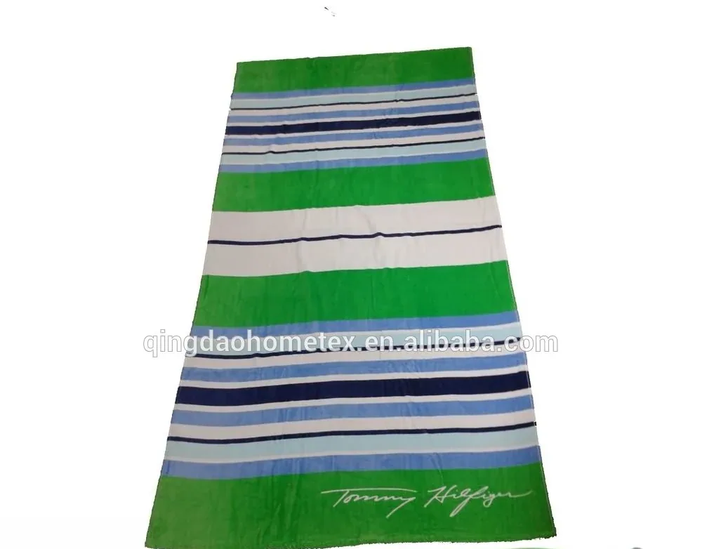 Green striped beach towel with a signature logo at the bottom.