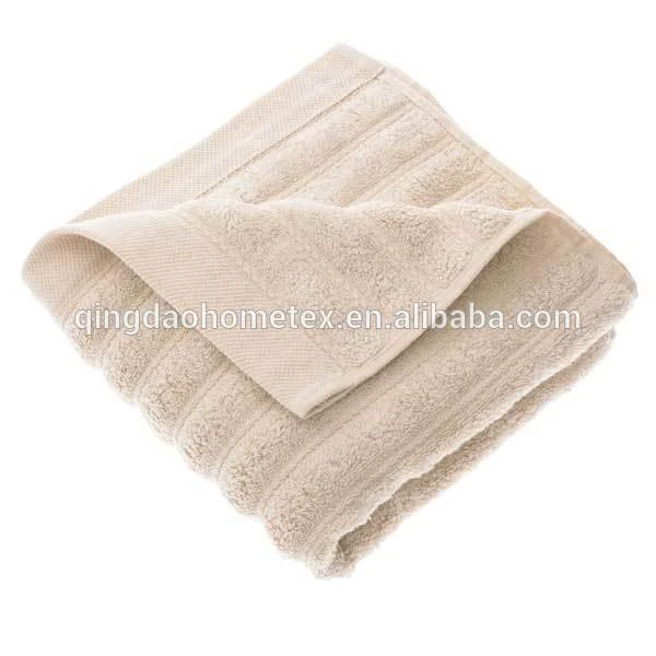 Folded beige cotton towel with ribbed texture and a flipped corner on a white background