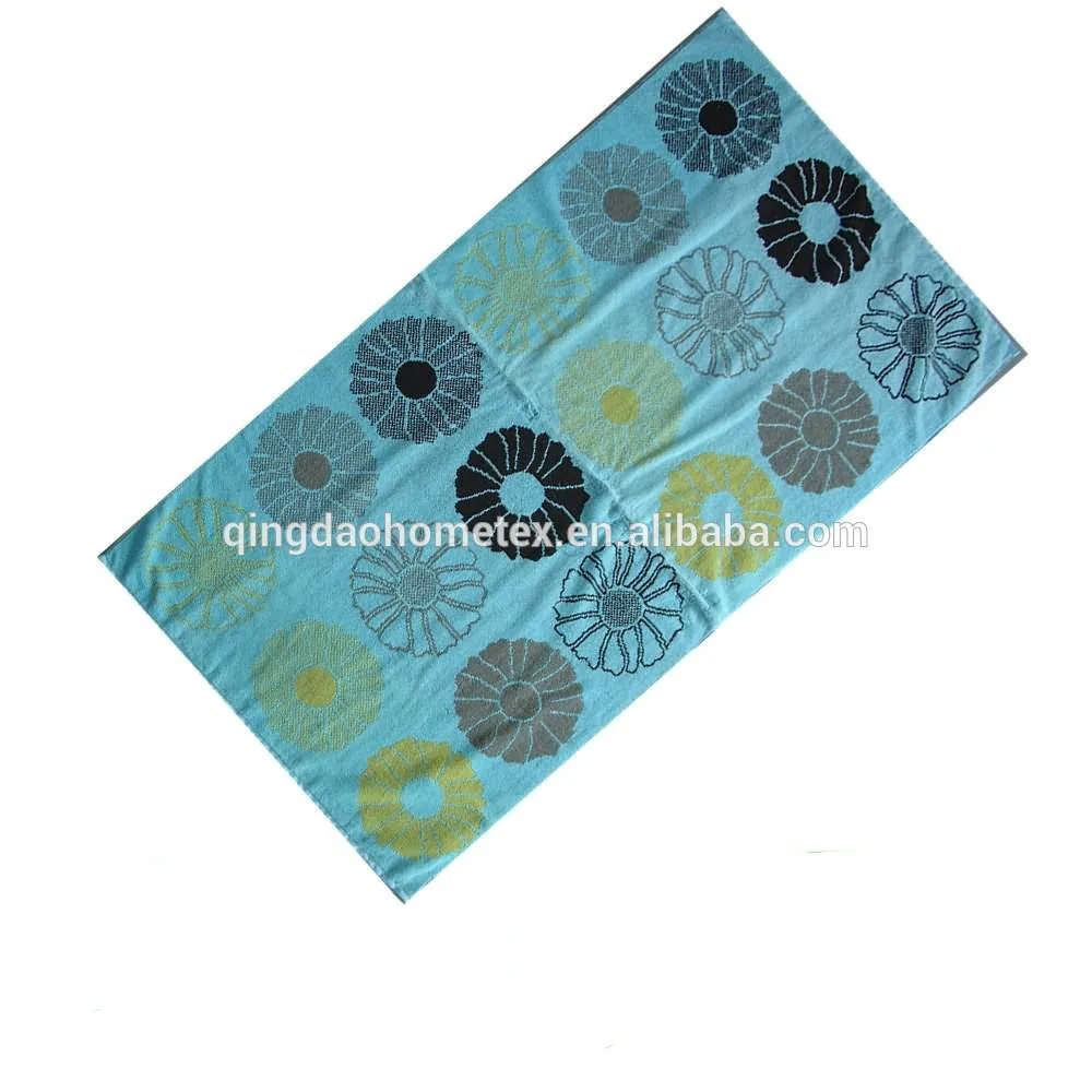 Teal towel with assorted daisy flower prints in black, gray and yellow, shown tilted on white background