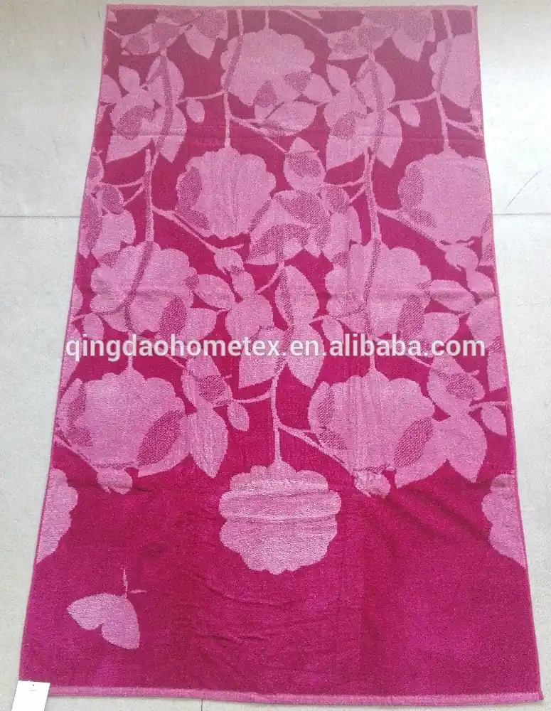 Magenta pink jacquard towel with light pink floral and butterfly pattern laid on a tiled floor