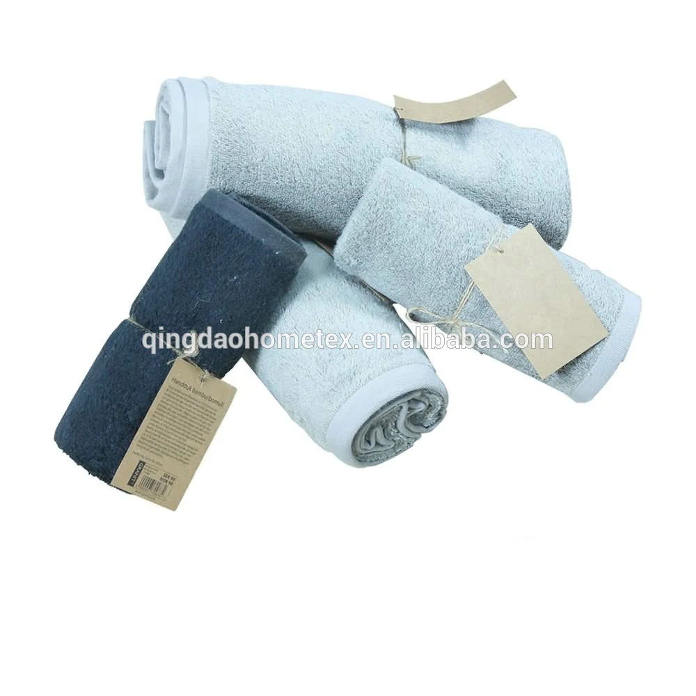 Rolled light and dark gray cotton towels with kraft paper tags on a white background