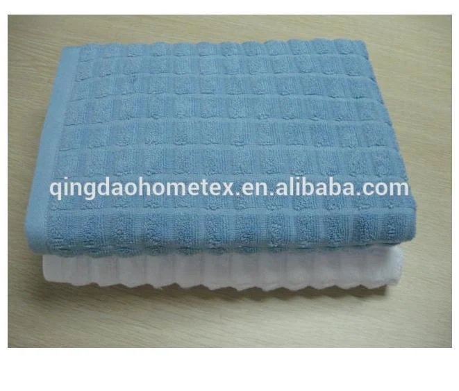 Folded blue waffle-weave towel stacked on top of a white towel on a wooden table surface