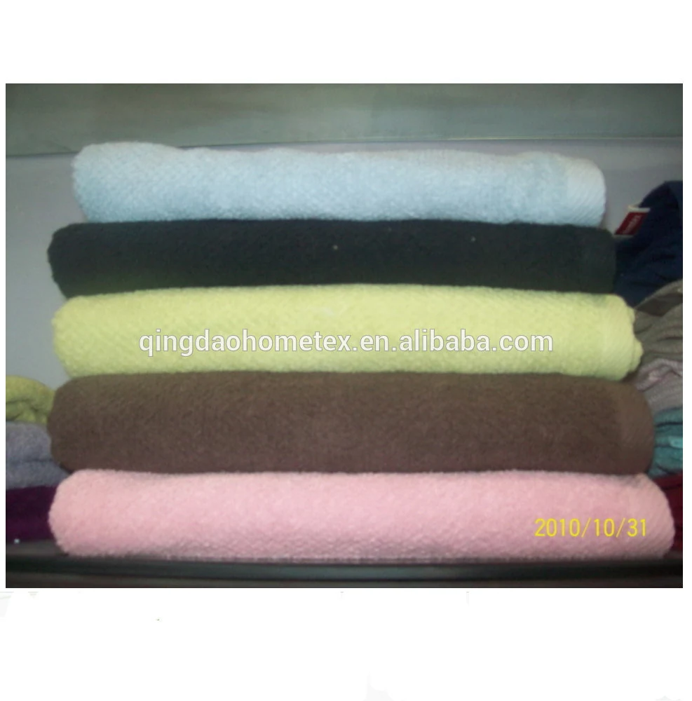Stack of folded towels in light blue, navy, yellow, brown and pink on a shelf