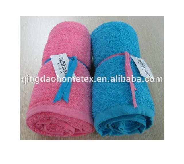 Two rolled terry towels, one pink and one blue, tied with ribbon bows and paper tags, on a light surface
